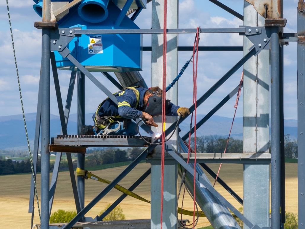 Top Bead Millwright welding at the top of a platform on a feed mill